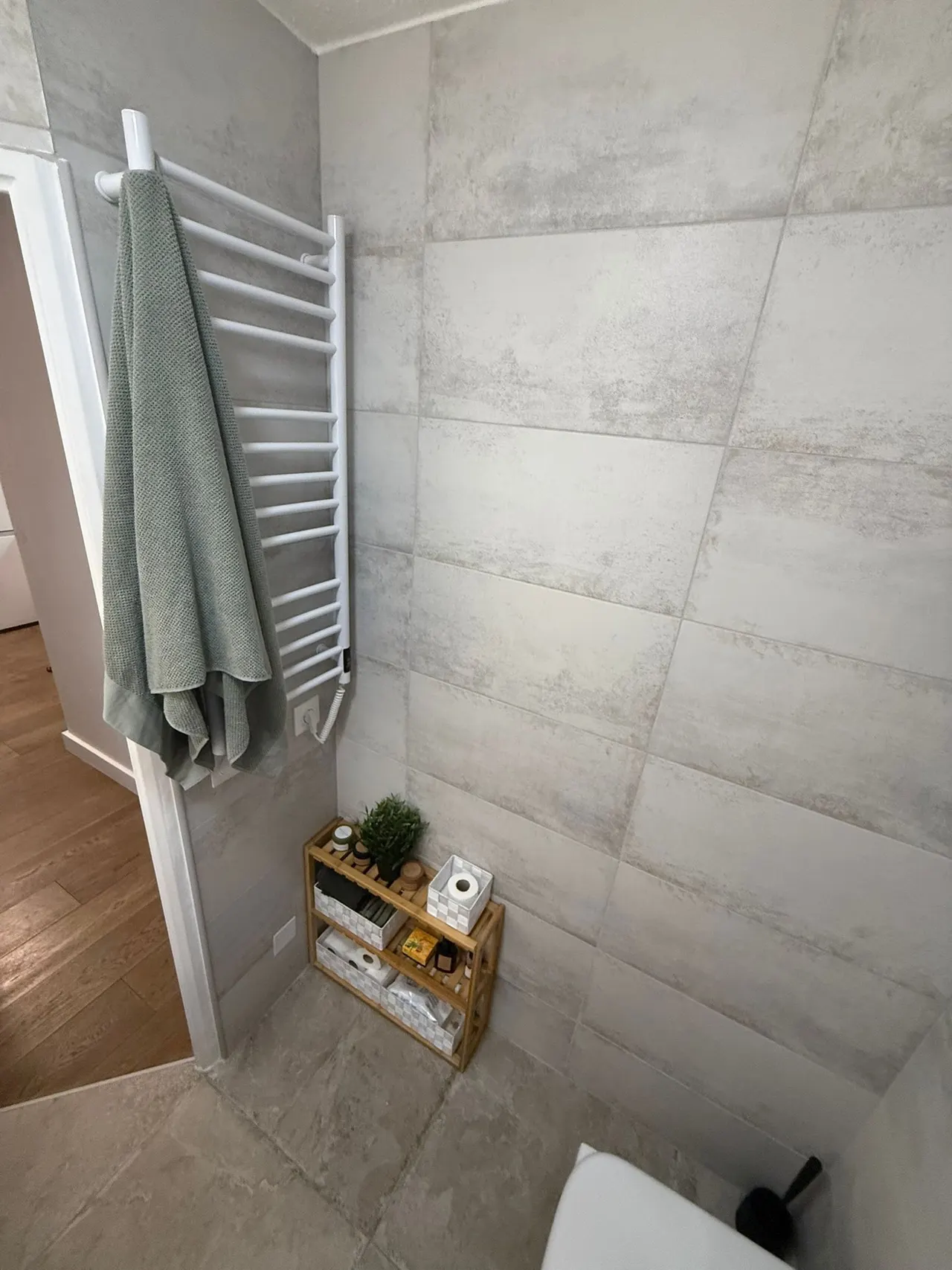 Großformatige Wandfliesen vom Boden bis zur Decke und Handtuchheizkörper im fertigen Bad